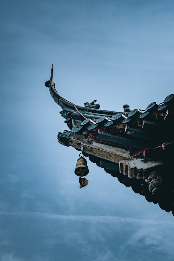 Traditional pagoda roof with ornament and bell under sky