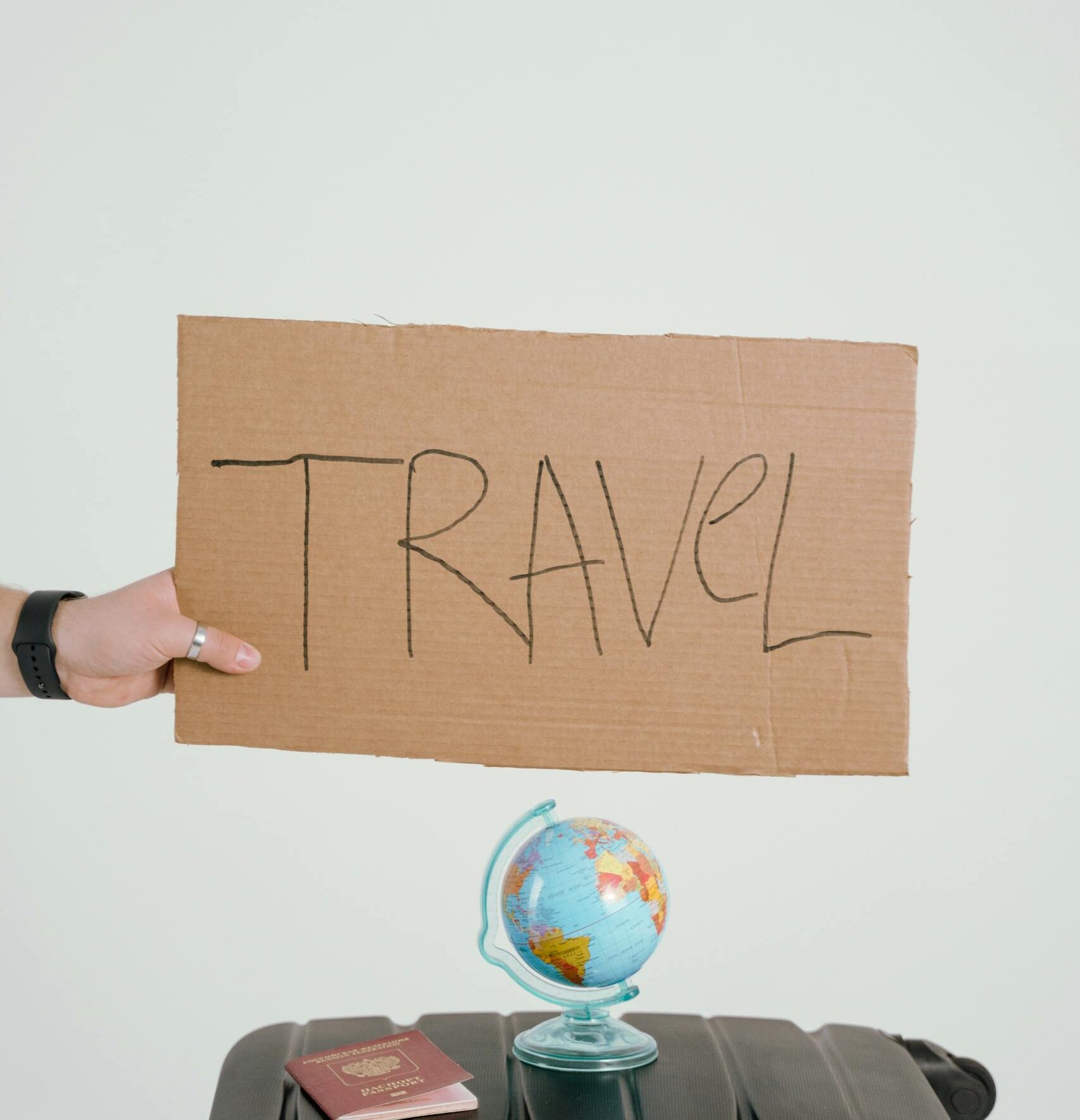 Person Holding Brown Cardboard with Travel Text